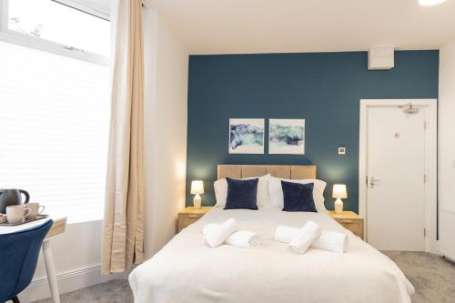 Suite 1 - Lovely Ensuite in Oldham Sociable House في أولدهام: غرفة نوم بسرير ابيض كبير بجدران زرقاء