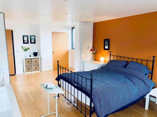 a bedroom with a blue bed and an orange wall at Designer Room with Private Bathroom in London