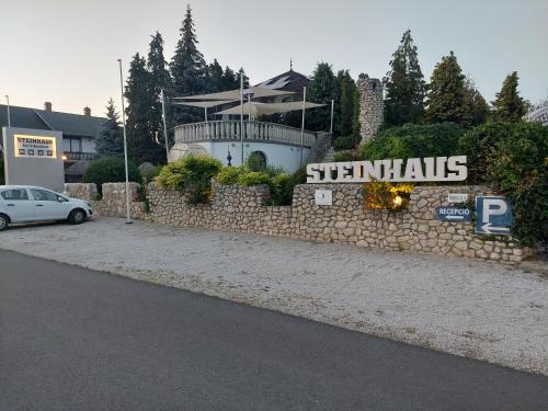 una pared de piedra con una señal frente a un edificio en Steinhaus Bed & Breakfast, en Keszthely