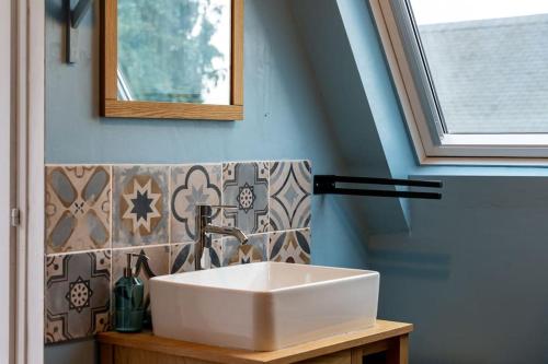 łazienka z białą umywalką i oknem w obiekcie Maisonnette & Jacuzzi w mieście Saint-Valéry-sur-Somme