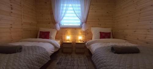 Habitación de madera con 2 camas y ventana en Grabska Osada SUN HOUSE - domki całoroczne ogrzewane en Grabce