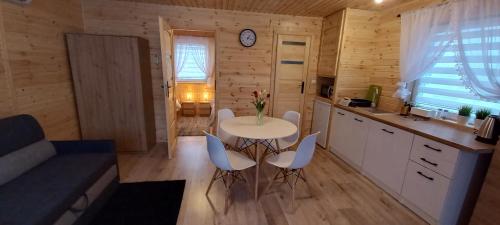 a kitchen with a table and chairs in a room at Grabska Osada SUN HOUSE - domki całoroczne ogrzewane in Grabce-Towarzystwo