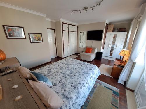 een slaapkamer met een bed en een bank in een kamer bij Peniche House in Atouguia da Baleia
