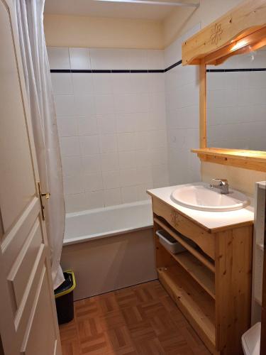 une salle de bain avec un lavabo et une baignoire dans l'établissement Appartement dans un chalet, résidence avec piscine, à La Toussuire