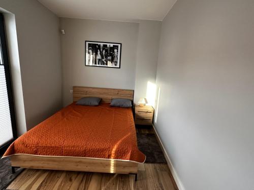 a bedroom with a bed with a orange bedspread at Sosnówka - Wypoczynek in Sosnówka