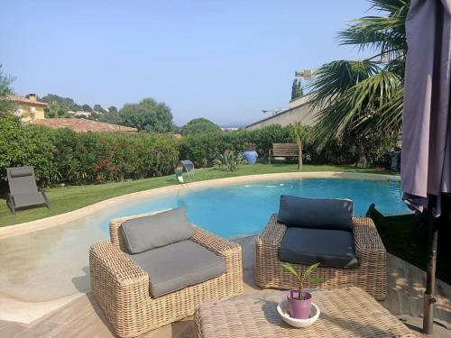 deux chaises et une table à côté d'une piscine dans l'établissement jolie villa avec vue mer, à Bormes-les-Mimosas