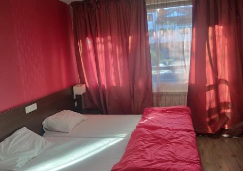 een slaapkamer met een bed met rode muren en een raam bij Igzila apartment in Banya