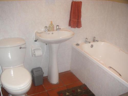 a bathroom with a sink and a toilet and a tub at Waterside Living MC03 in Jeffreys Bay