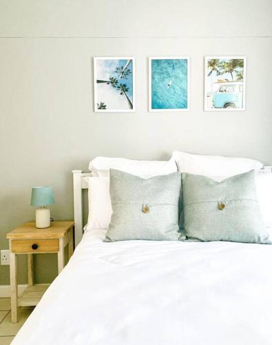 a bedroom with a white bed with pillows and a table at Ocean Escape in Strand