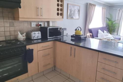 a kitchen with a black counter top and a microwave at Ocean Escape in Strand