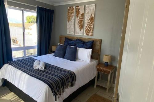 Un dormitorio con una cama con almohadas azules y una ventana en Ocean Escape, en Strand