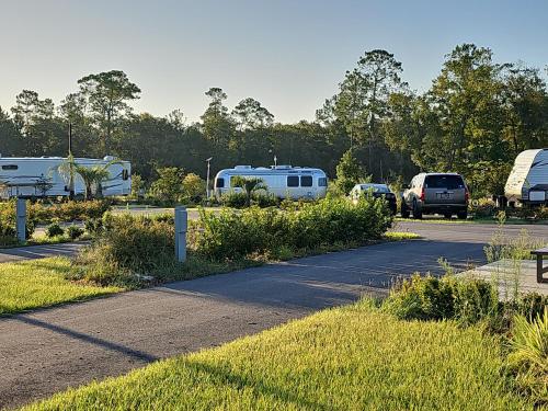 ein Parkplatz mit zwei Wohnwagen und geparkten Fahrzeugen in der Unterkunft Santa Fe Palms RV Resort in Gainesville