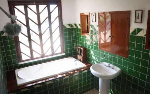 baño de azulejos verdes con bañera y lavamanos en The Octopus's Garden Hostel en Cruz de Huanacaxtle