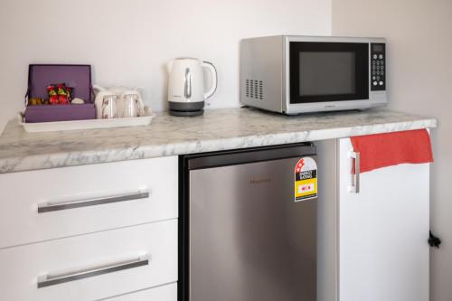 a kitchen with a stainless steel dishwasher and a microwave at West Swan B&B in Perth