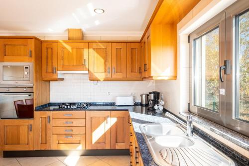 a kitchen with wooden cabinets and a sink at VILLA Simao in Guia