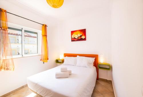 1 dormitorio con cama blanca y ventana en Milene Guest House, en Albufeira