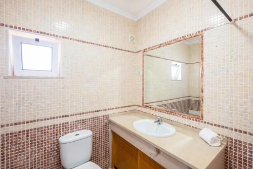 bagno con servizi igienici, lavandino e specchio di Milene Guest House ad Albufeira
