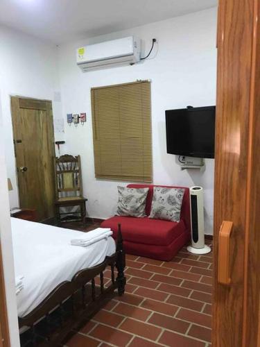 a room with a bed and a couch and a tv at Apartamento Concepción Mompox in Mompós