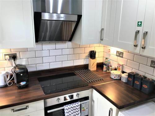 uma cozinha com armários brancos e um forno com placa de fogão em Newly Refurb Period 1-Bed Apartment with Roof Terrace, 47 sqm-500 sqft, in Putney near River Thames em Londres