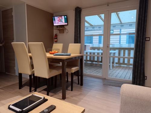 a dining room with a table and chairs and a balcony at mobil home 3 chambres 152 in Pont-Aven