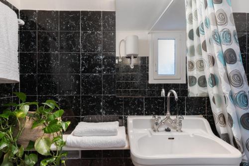 uma casa de banho em azulejos pretos com um lavatório e uma janela em Lovely Apartment in Exarcheia em Atenas
