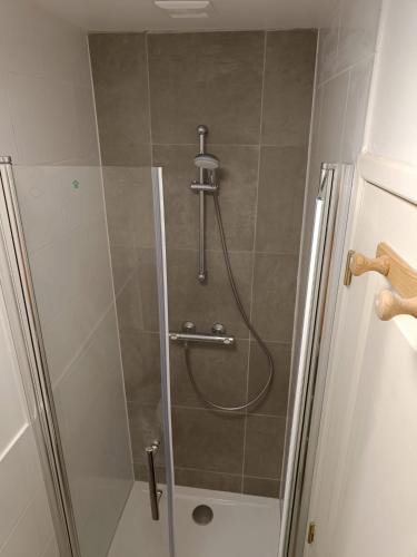 une douche avec une porte vitrée dans une salle de bain dans l'établissement Maison La Motte with bicycle parking, à Saint-Hilaire-du-Harcouët
