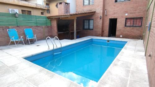 ein Pool mit zwei blauen Stühlen neben einem Gebäude in der Unterkunft casa villa suiza in Villa Carlos Paz