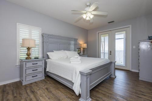Un dormitorio con una cama blanca y un ventilador de techo. en Hideaway Bay, en Gulf Highlands