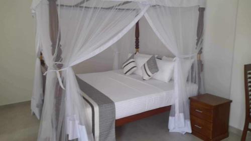 a bedroom with a canopy bed with white curtains at Villa Wasana - Galle in Galle