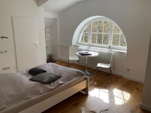 een slaapkamer met een bed en een gewelfd raam bij Villa Schöneck in Windeck