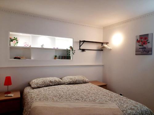 1 dormitorio con 1 cama, ventana y estanterías en La casa del largo del rosso, en Pozzuoli
