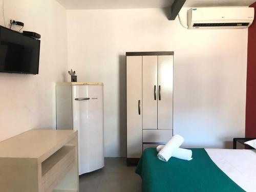 een kamer met een bed, een koelkast en een televisie bij Babeu suites independentes in Rio de Janeiro