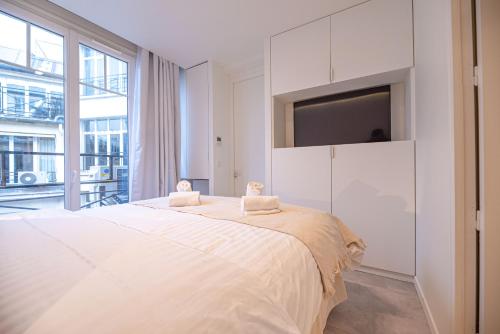 - une chambre blanche avec un grand lit et une grande fenêtre dans l'établissement Amazing flat - CHAMPS ELYSEES, à Paris