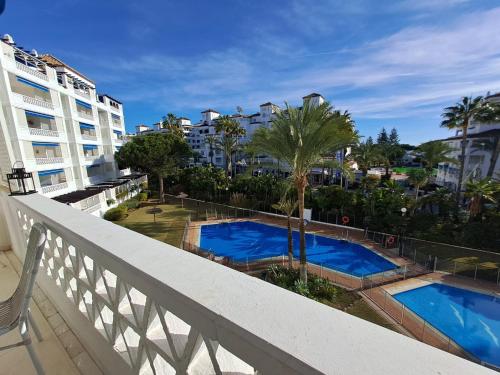 a balcony with two pools and palm trees and buildings at Luxury Apartment in Playas del Duque , Puerto Banus by Holidays & Home in Marbella