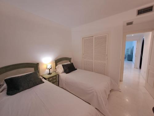 um quarto com duas camas e um candeeiro sobre uma mesa em Luxury Apartment in Playas del Duque , Puerto Banus by Holidays & Home em Marbella
