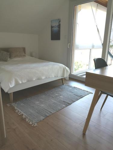une chambre avec un lit, un bureau et une fenêtre dans l'établissement Appartement douillet (3 étoiles) à 5 min du lac, à Sévrier