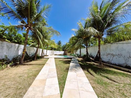 un chemin avec des palmiers devant un mur dans l'établissement Casa Praia da Caponga, à Cascavel