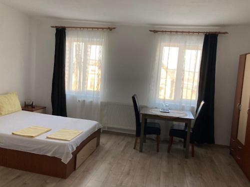ein Schlafzimmer mit einem Bett, einem Tisch und einem Schreibtisch in der Unterkunft ,, LA MAISON CONCORDIA '' in Cincu