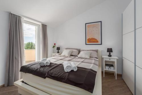 een witte slaapkamer met een bed met handdoeken erop bij Residence David in Poreč
