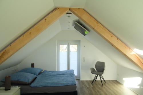 um quarto no sótão com uma cama e uma cadeira em Ferienhaus mit Alpenpanorama em Deggenhausertal