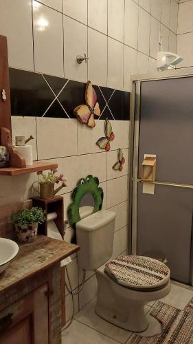 a bathroom with a toilet with butterflies on the wall at Hostel da Jô in Chapada dos Guimarães