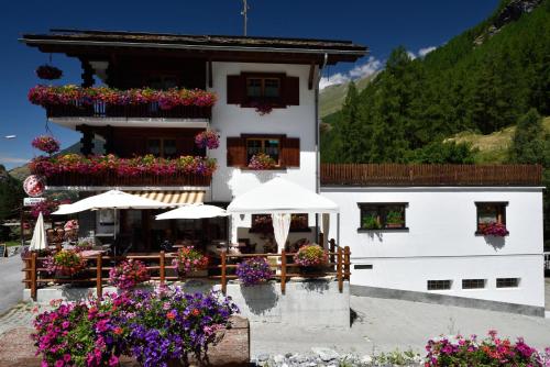 a building with umbrellas and flowers in front of it at Hotel Les Mélèzes in Haudères