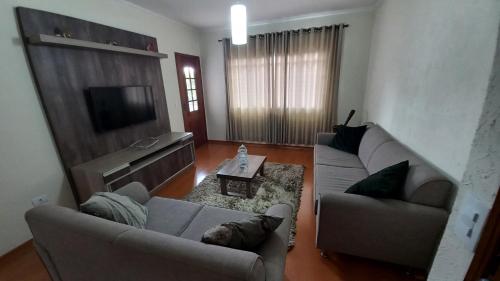 a living room with two couches and a television at Conforto e Tranquilidade in Poços de Caldas