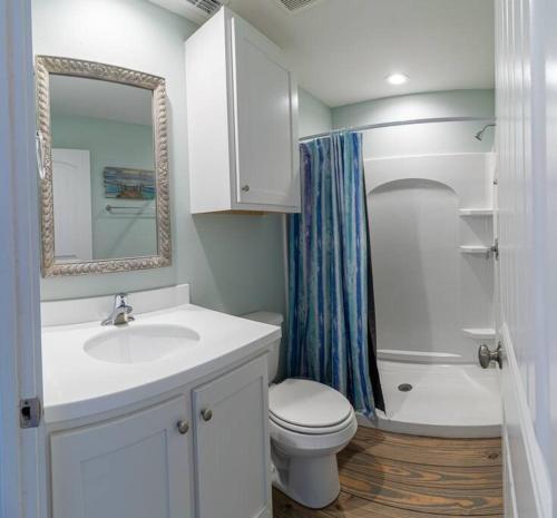 a bathroom with a sink and a toilet and a mirror at Beach Bungalow - 2 Suns in Port Aransas