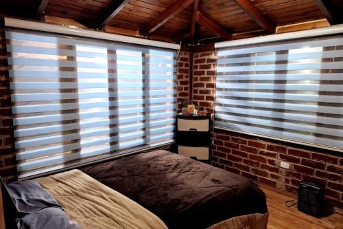 a bedroom with two large windows with blinds on them at Villa Don Alonso: Casa de Campo in Penipe