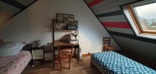 Schlafzimmer mit einem Bett, einem Schreibtisch und einem Fenster in der Unterkunft Guim appart in Guimiliau
