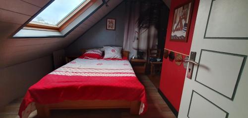 a bedroom with a bed with a red comforter and a window at Guim appart in Guimiliau