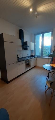 een keuken met witte kasten en een tafel in een kamer bij Lichtdurchflutetes Apartment mit Parkplatz in Mülheim an der Ruhr