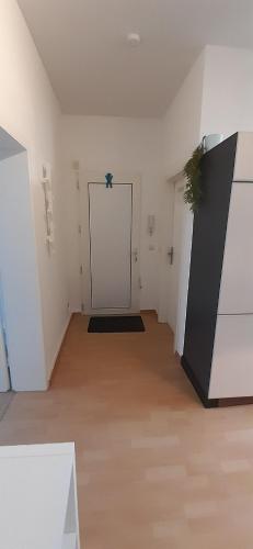 een lege kamer met een witte deur en een houten vloer bij Lichtdurchflutetes Apartment mit Parkplatz in Mülheim an der Ruhr