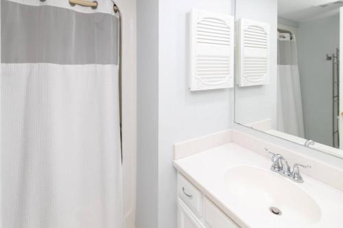 a white bathroom with a sink and a mirror at Great beach GETAWAY. Walking distance of the Beach in Hilton Head Island